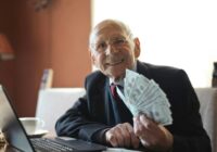 Happy senior businessman showing cash at his desk with a laptop, indoors., tags: nel - pexel
