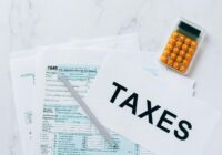 Top view of tax forms, a calculator, and pen for tax preparation., tags: limiti il - pexel