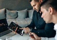 Two business professionals using a laptop and tablet to analyze online trading data indoors., tags: mercati strategie la - pexel